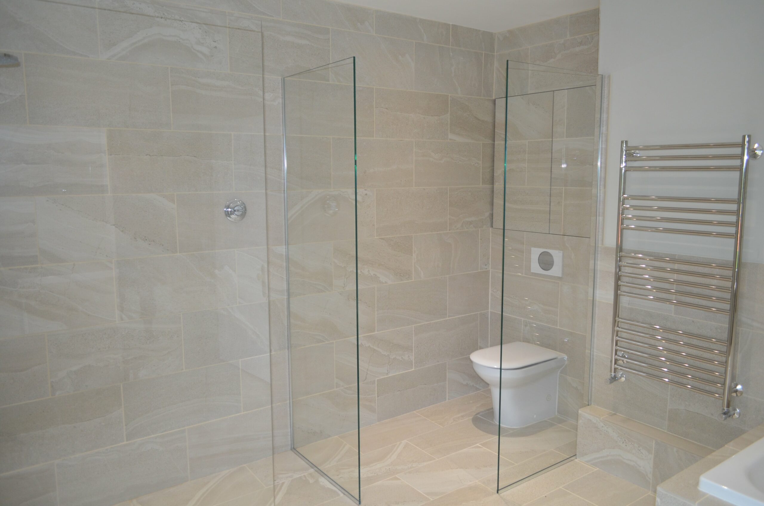 bright open neutral bathroom with walk in shower and glass panel to separate toilet