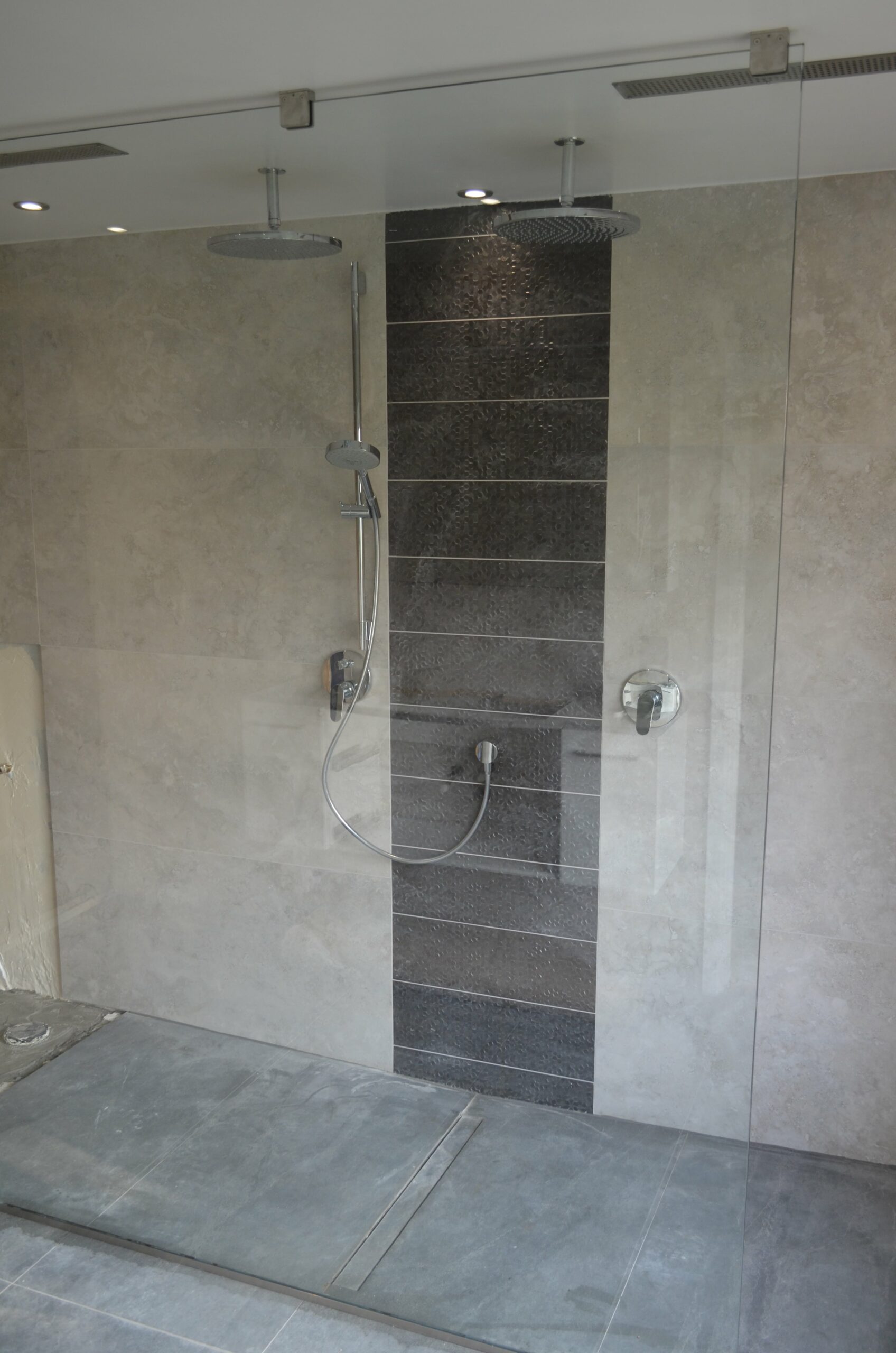 walk in shower enclosure with granite and concrete tiles