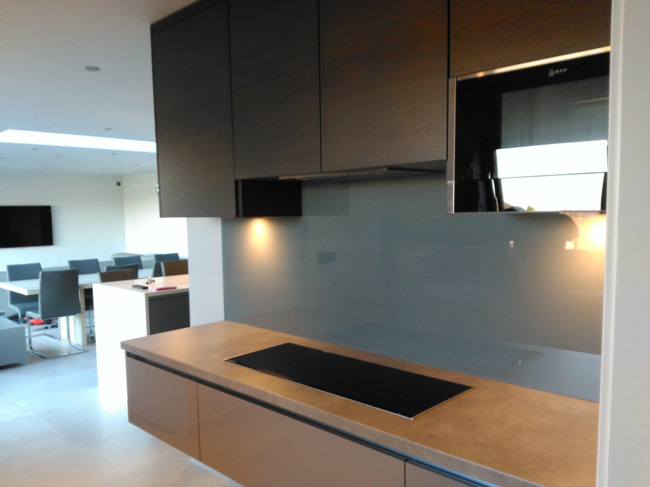 matte charcoal kitchen units with floating worktops and a blue grey splashback