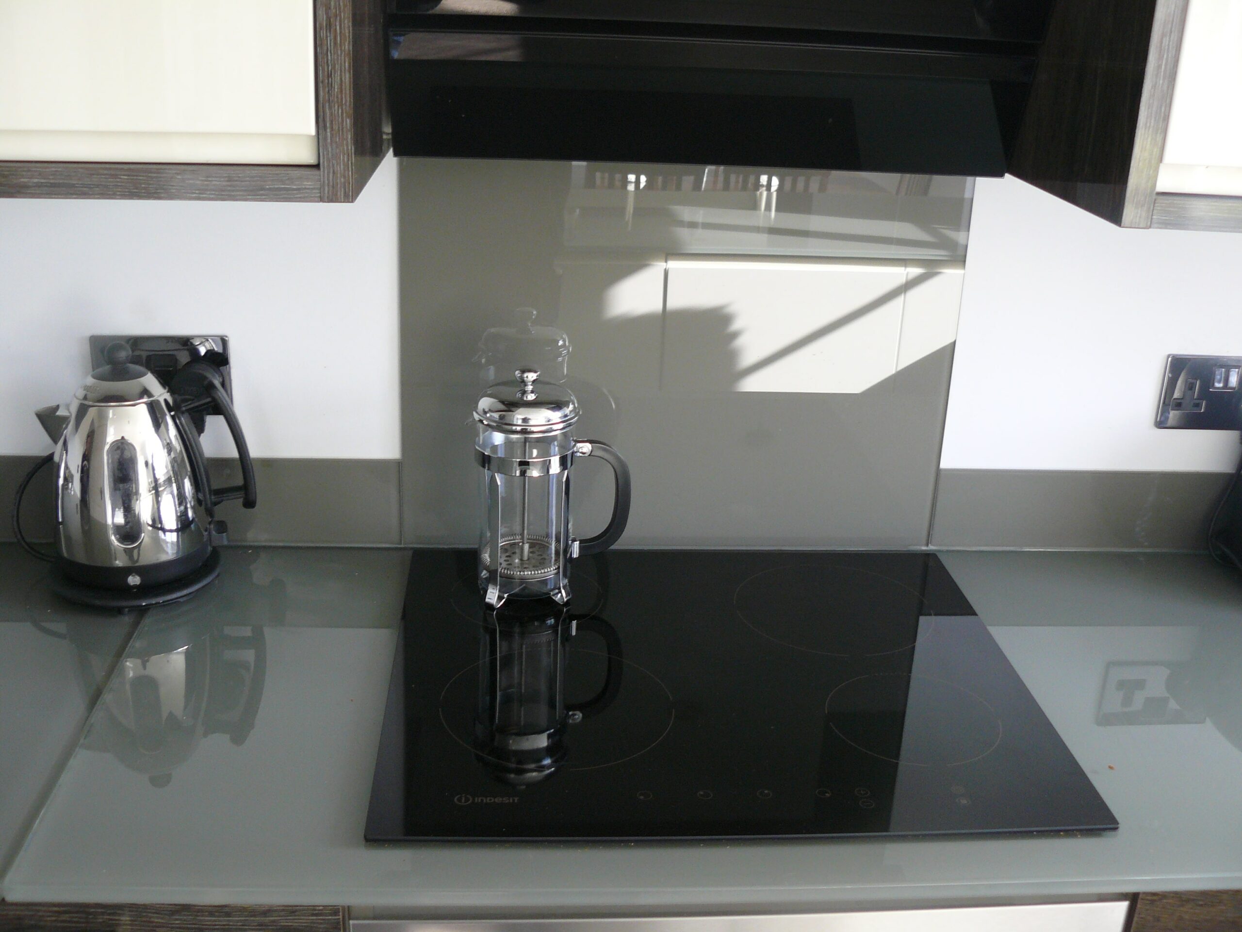 grey splashback and glass worktops in kitchen around the induction hob