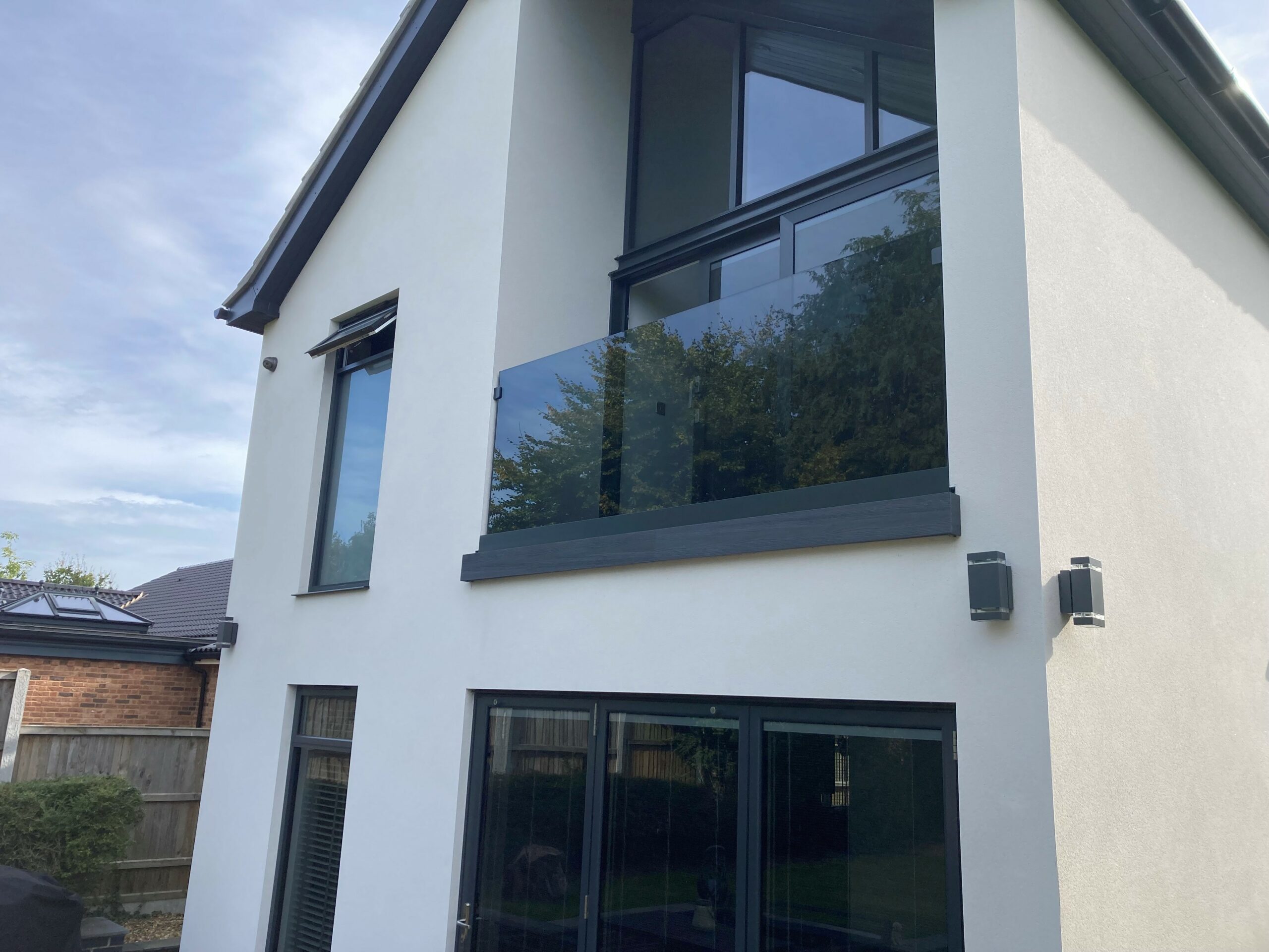 modern wroxham house with built in balcony with grey tinted glass