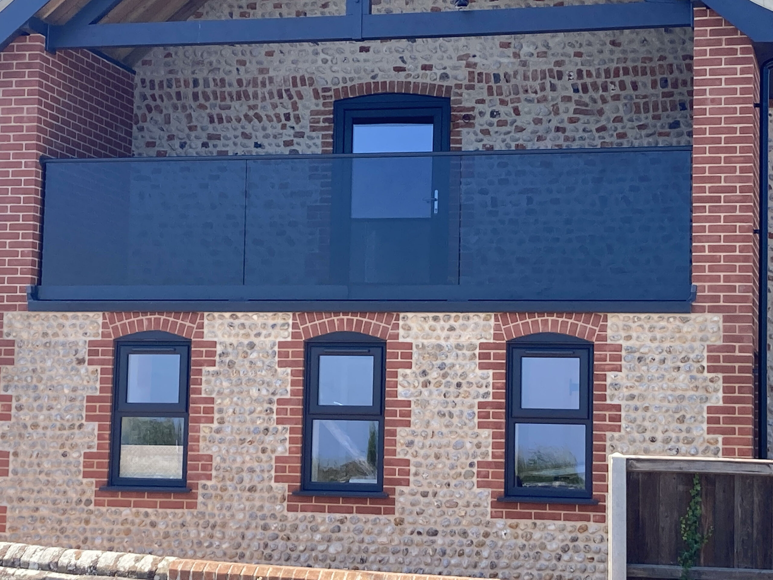 grey tinted glass for built in balcony on front of large home