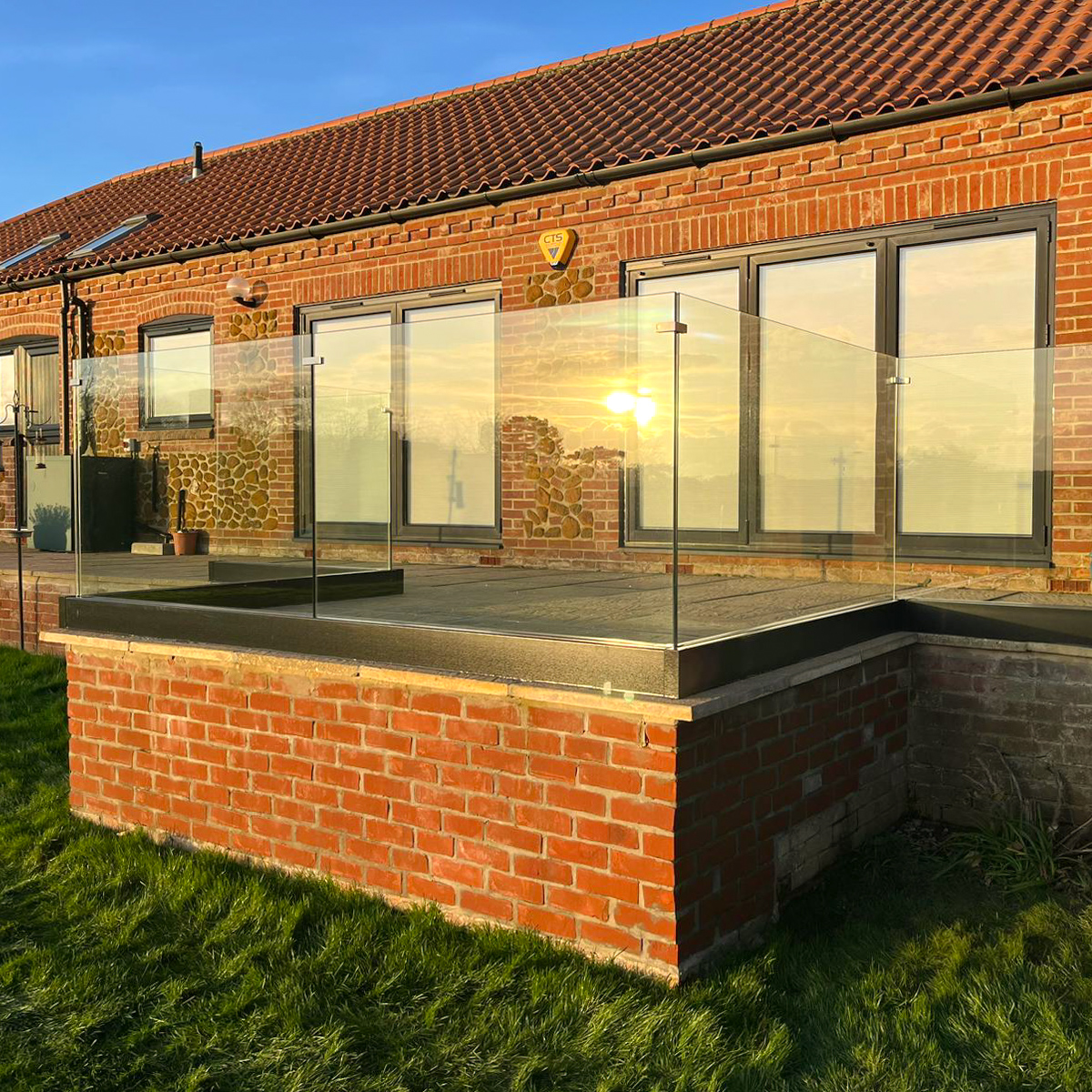 glass balustrade surrounding patio at the back of the house in the golden hour sun