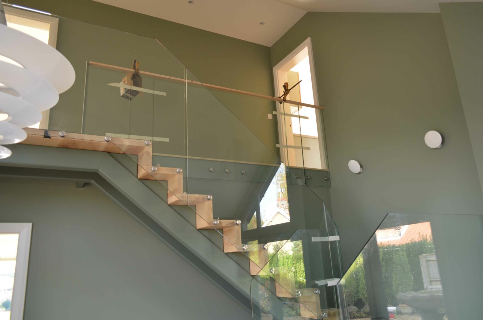 clear frameless glass staircase with wooden steps and grey wall