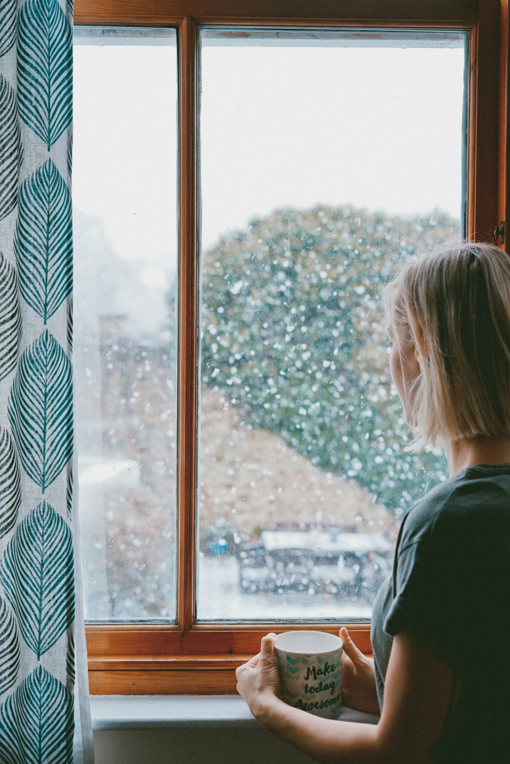 Woman at window with mug in hands