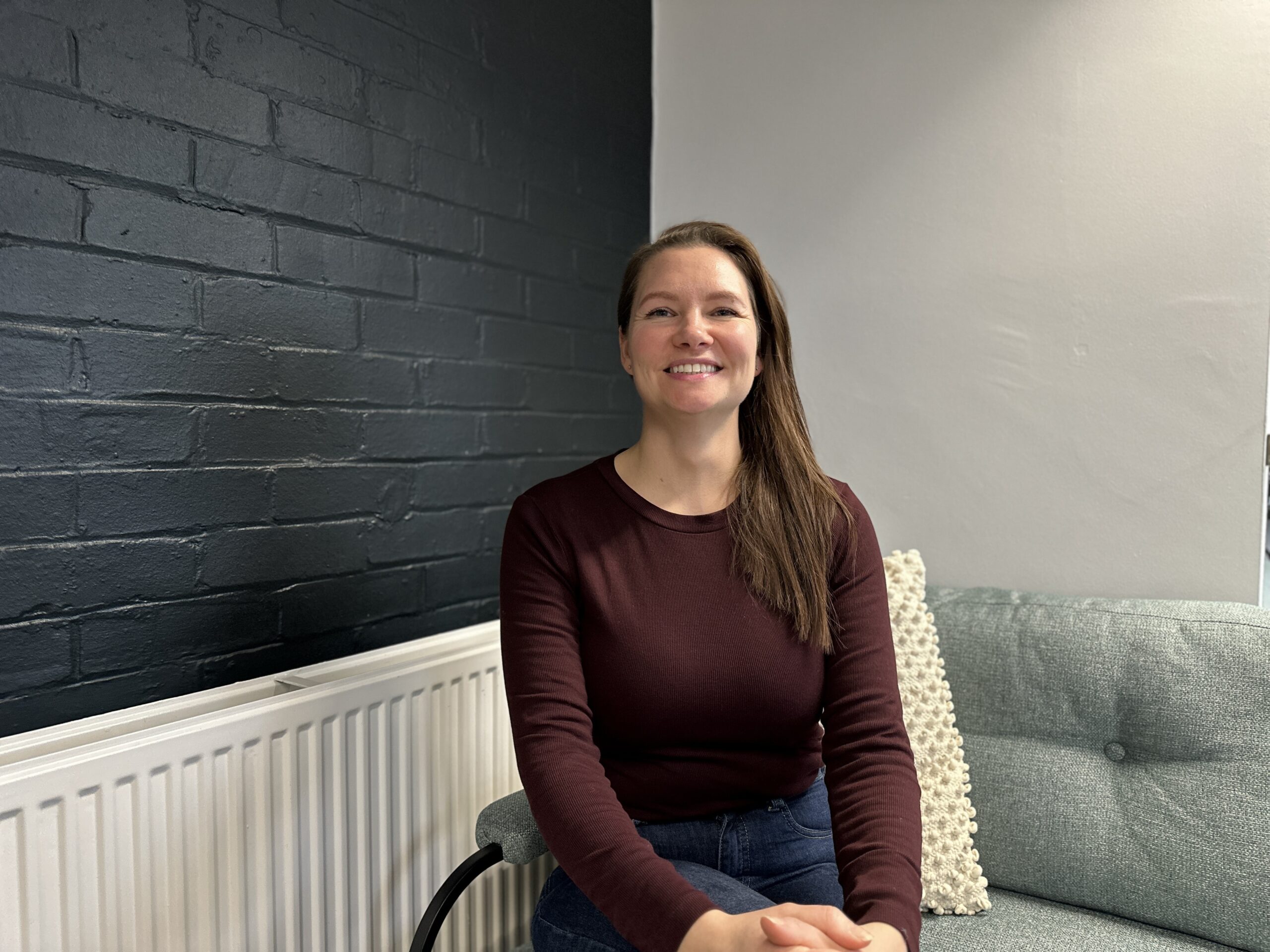 Carly from Norwich Glass sitting on a sofa against black and white walls