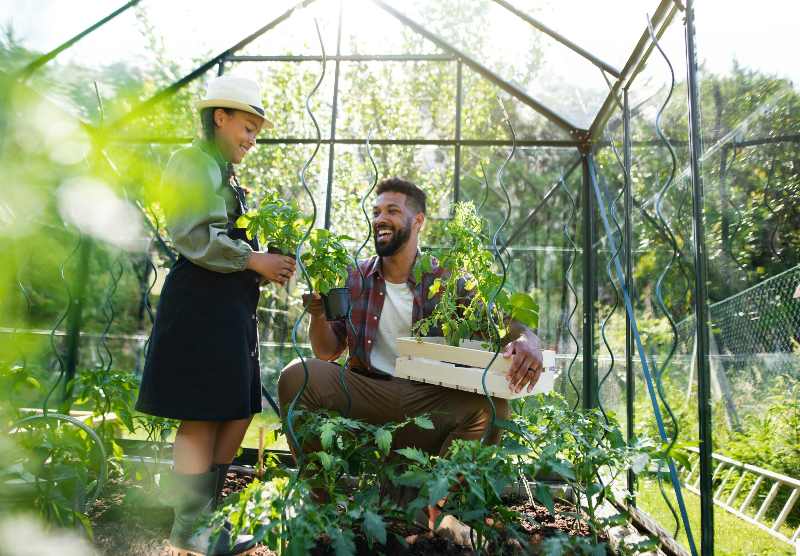 Man and young daughter in greenhouse holding plants